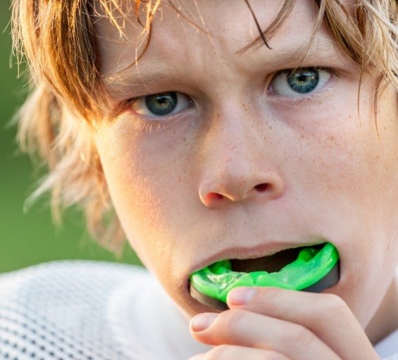Young boy placing athletic mouthguard into his mouth
