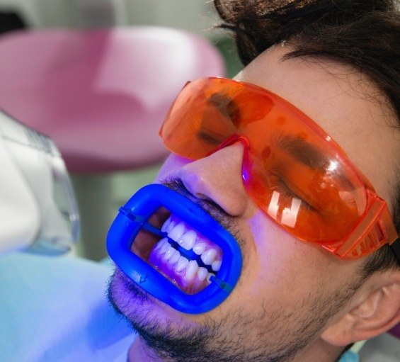 Man receiving professional teeth whitening while visiting cosmetic dentist