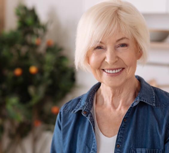 A cheerful older woman standing in a kitchen