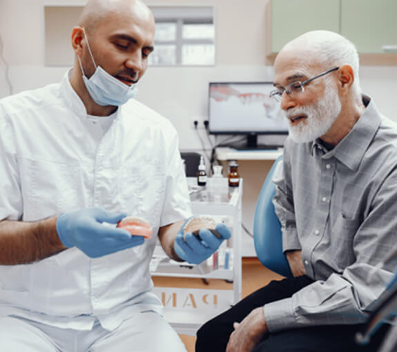 An older man consulting his dentist about implant dentures